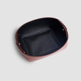 Minimalist brown leather valet tray with raised sides on a light grey background