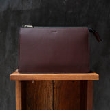 Macro shot of vegetable-tanned Italian leather edges showing hand-painted burnished finish of travel pouch bag