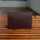 Sandal Wood leather travel pouch with monogrammed initials on front, shown with keys and AirPods