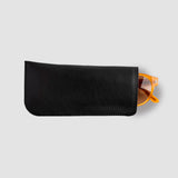 Black leather sunglasses case with orange sunglasses on a light gray background