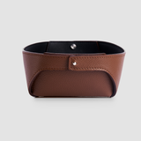 Brown full-grain leather valet tray with black interior on a grey background