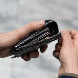 Open black leather wallet revealing two compartments – top section for cards, lower zippered area for bills and coins.
