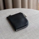 Macro shot of full-grain Italian leather texture and hand-stitched edges on black wallet.