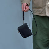 Hand holding black leather zip wallet with chain clipped to belt loop for secure access.