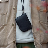 Black Italian leather zip wallet closed, showing sleek minimalist design with silver YKK zipper and detachable cord