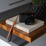 Brown leather camera strap beside vintage film camera and credit card - slim 1.2cm width shown for scale