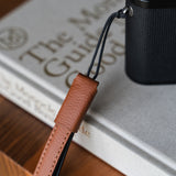 Photographer using brown leather camera strap with mirrorless camera in outdoor setting - practical and stylish carry solution
