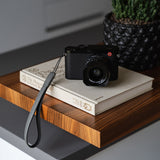 Close-up of gray full-grain leather texture and hand-stitched seams on OCULT camera strap - shows premium craftsmanship