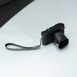 Photographer using gray leather camera strap with vintage film camera in urban setting.