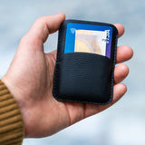 Minimalist black leather card holder with slim profile and central opening, handcrafted by OCULT for everyday essentials.