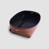 Brown leather valet tray viewed at an angle, showing its shape and raised edges