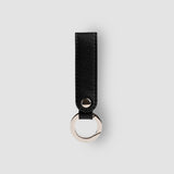 Black leather keychain with silver ring on a light gray background