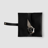 Black leather watch case with a silver watch on a light gray background